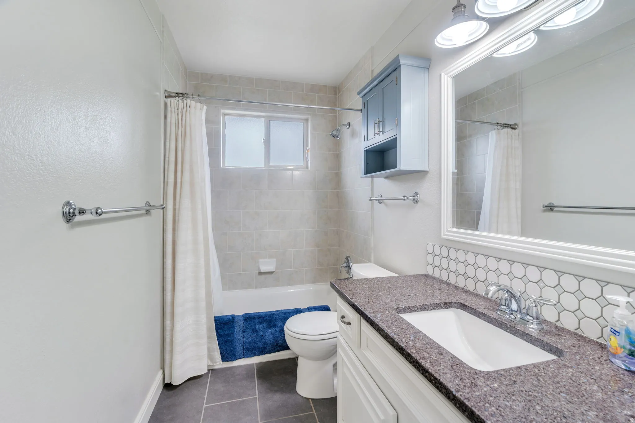 Bathroom featuring a vanity with an integrated sink, a speckled countertop, and a geometric tile backsplash