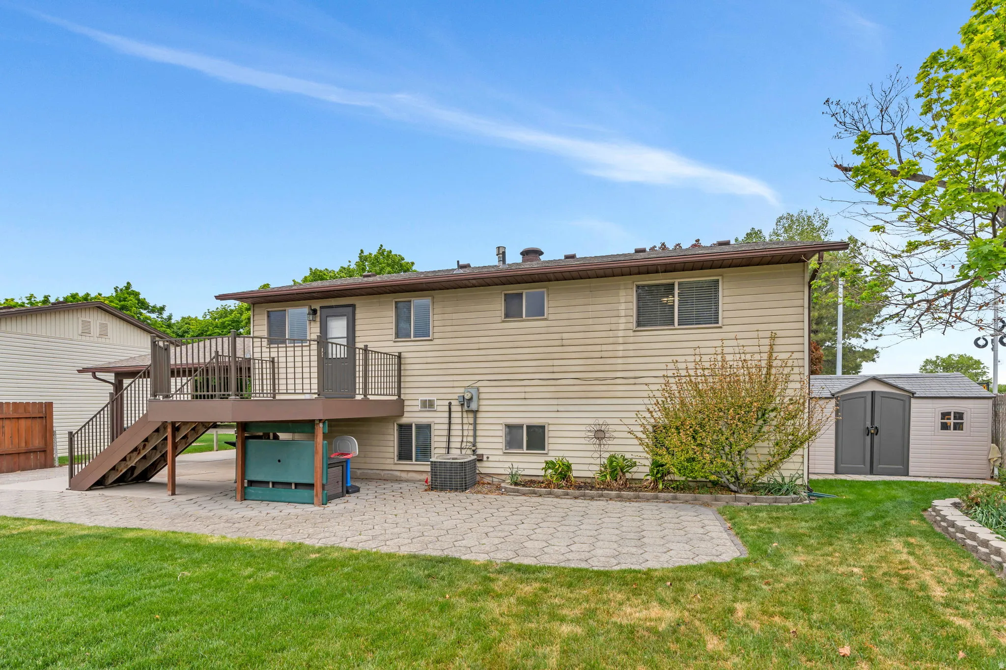 Backyard featuring a paver patio and a raised deck with dark railings