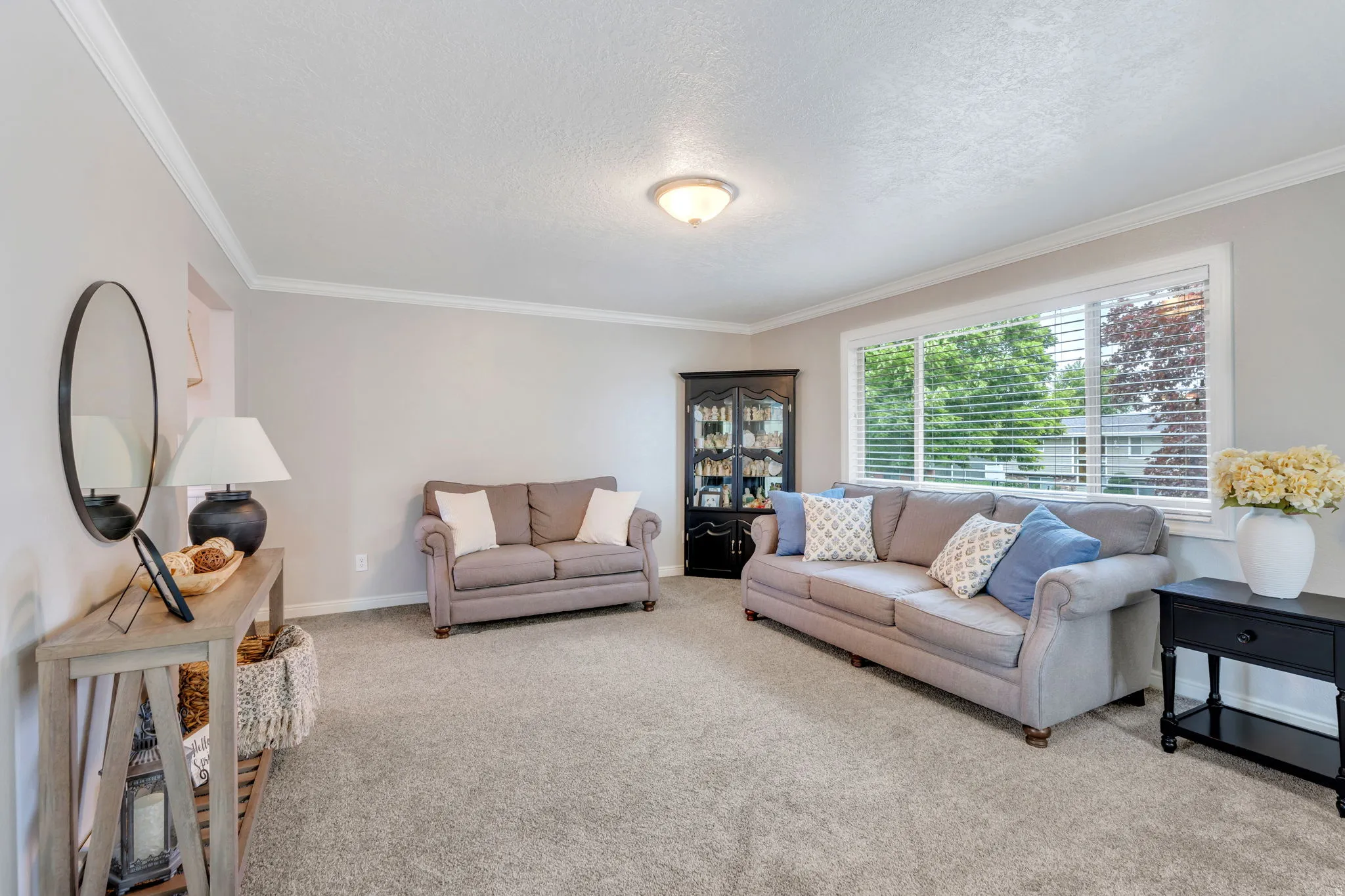 Spacious room featuring light gray walls, white crown molding, and gray carpeted flooring