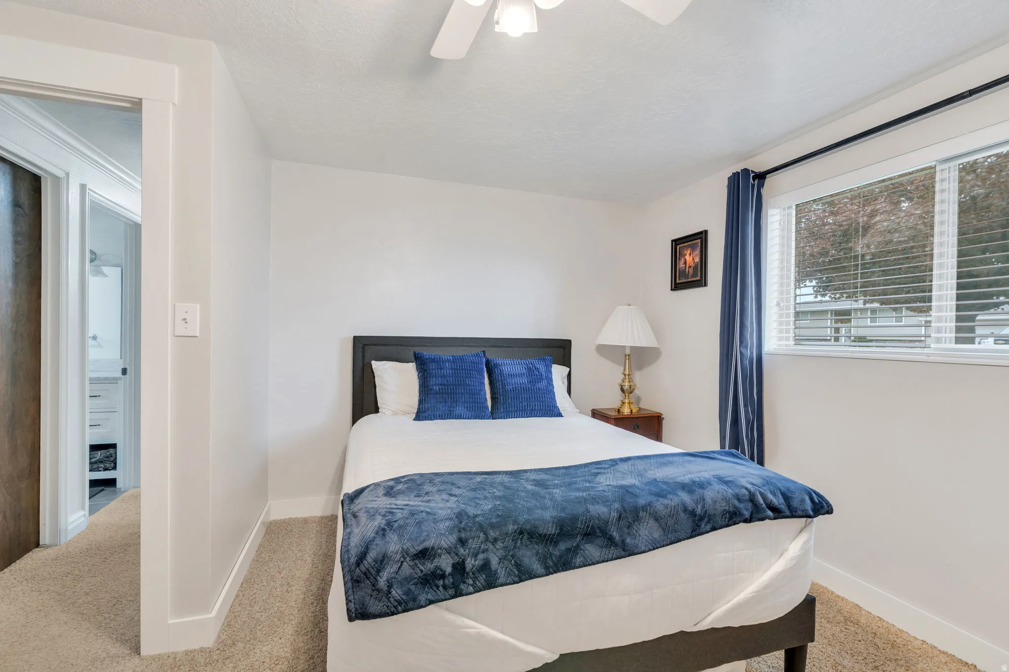White painted walls with white trim, tan carpeting, and a ceiling fan with integrated lighting