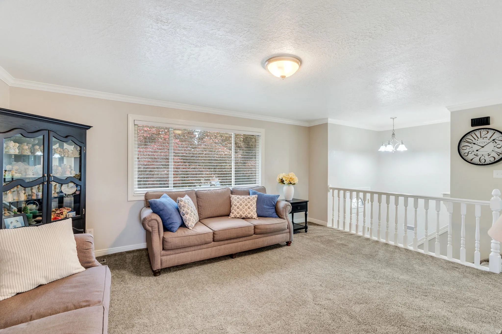 Carpeted room with crown molding and a large window with blinds