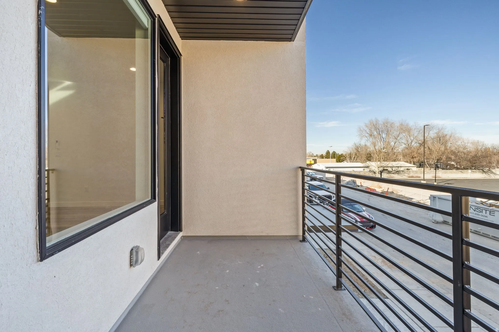 Outdoor balcony featuring a metal railing system, stucco exterior, and overhead soffit with recessed lighting