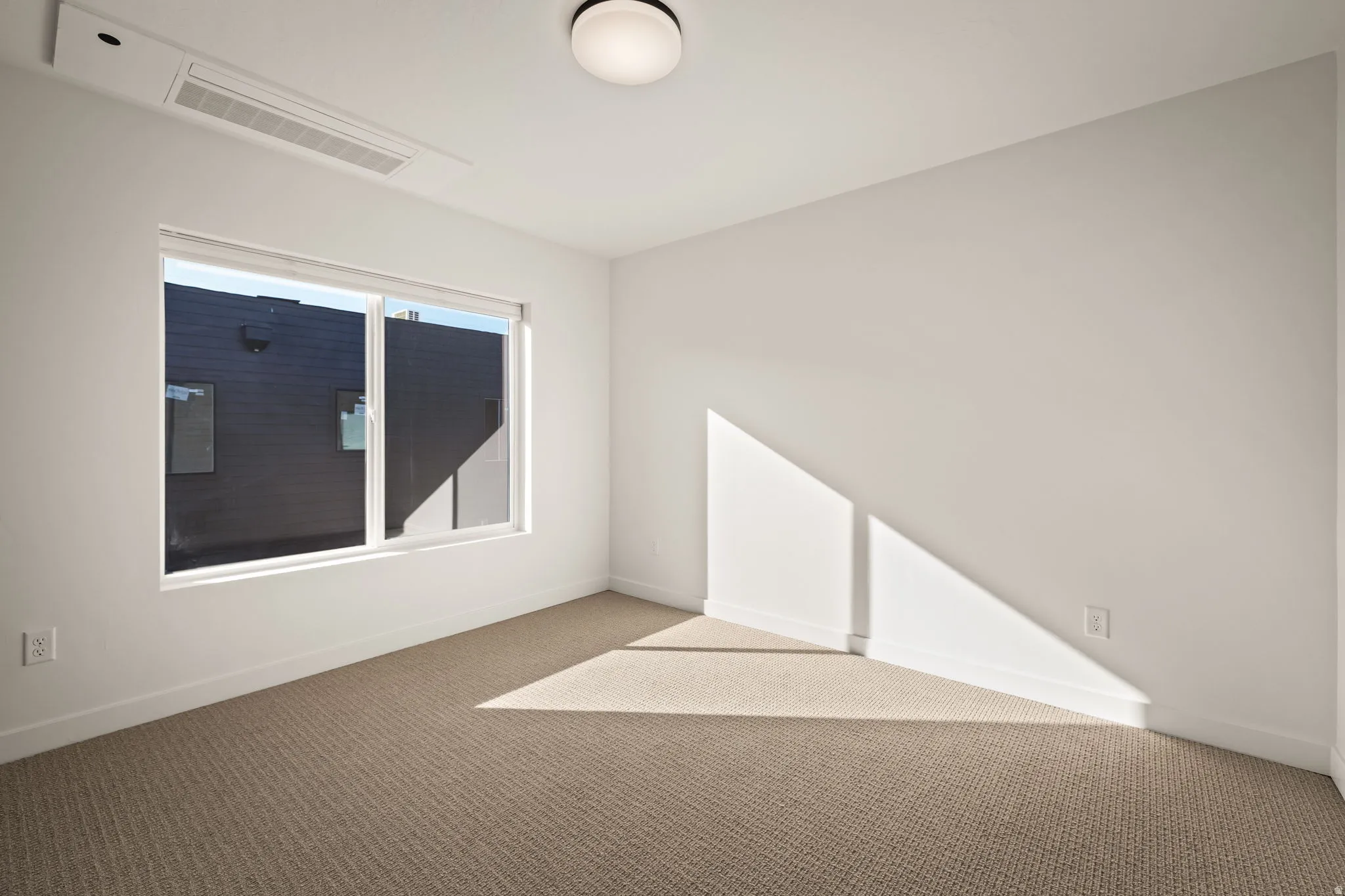 Spacious room featuring neutral carpeting and white baseboards