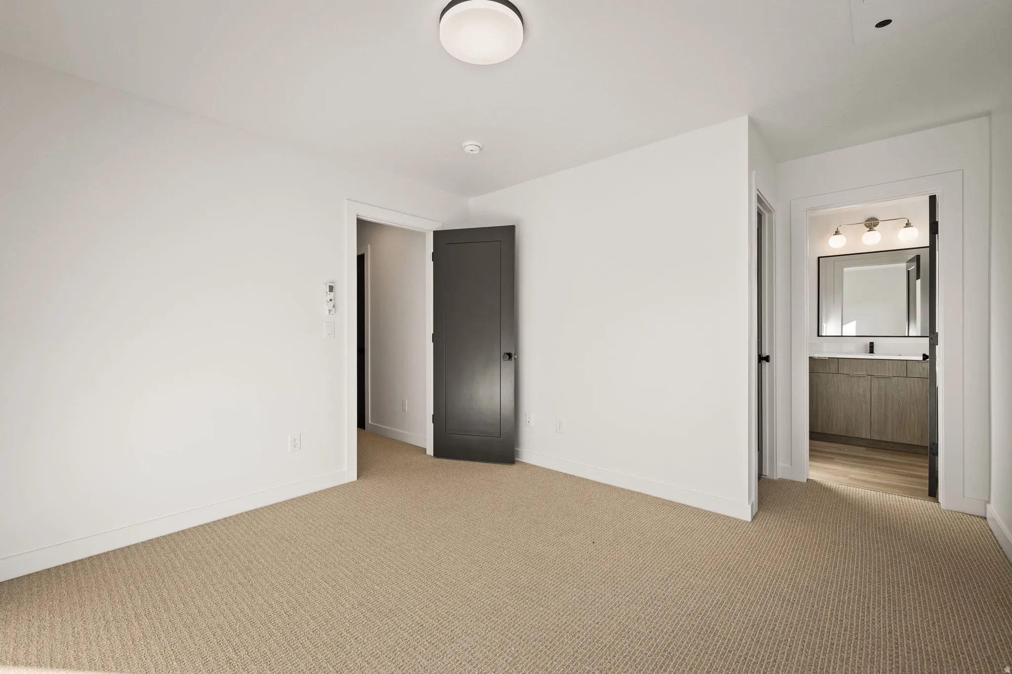 Carpeted room featuring white walls and a contemporary flush-mount ceiling light