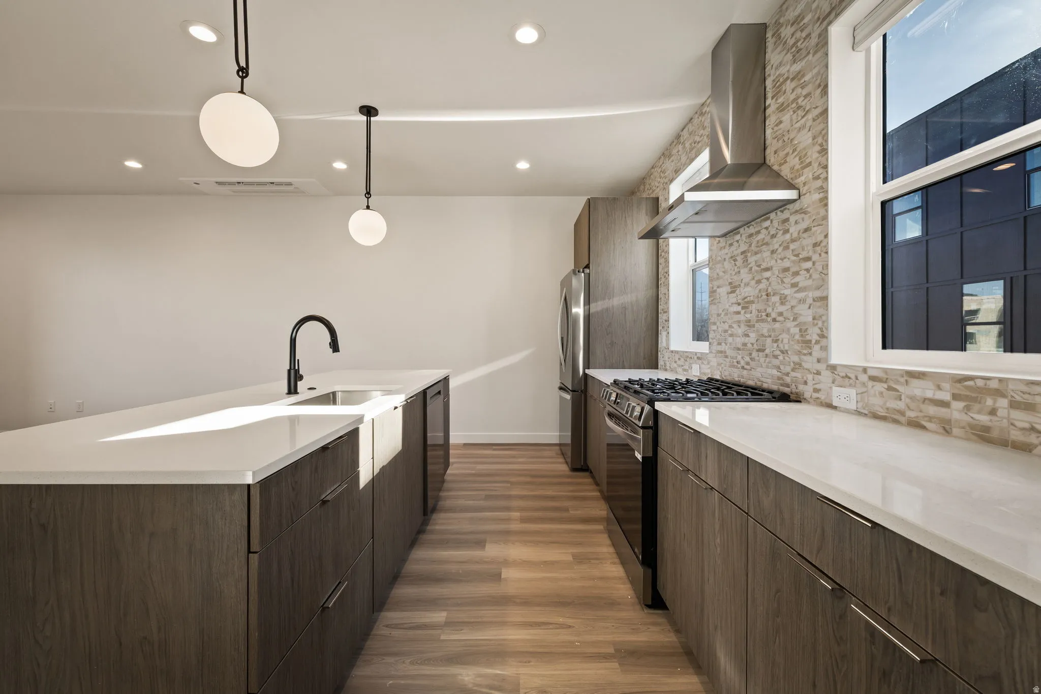 Modern kitchen featuring wood-finish cabinetry, light-toned countertops, and a stone-patterned backsplash