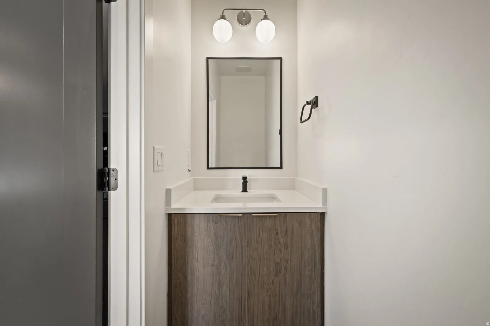 Modern bathroom vanity with wood-finish cabinetry, a white countertop, and an undermount sink
