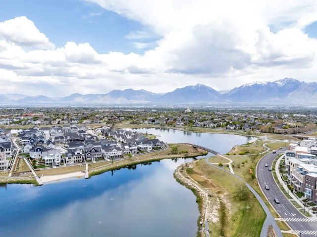 Lakeside community featuring residential properties, a paved road, and a pedestrian bridge over water