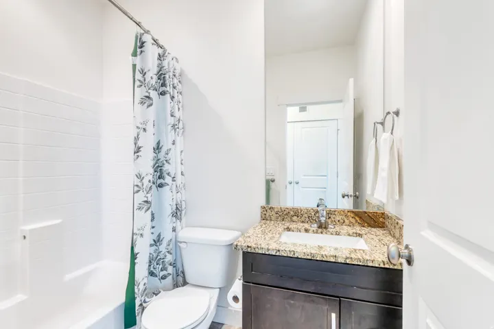 Bathroom featuring a vanity with a granite-style countertop, an undermount sink, and a dark wood-finish cabinet