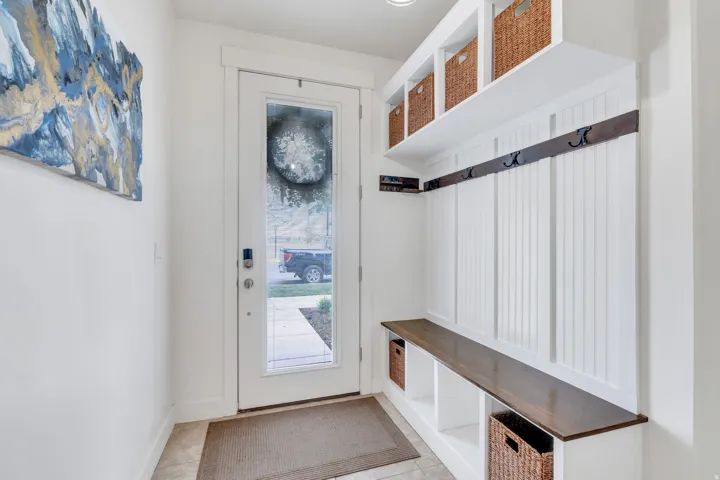 Entryway featuring built-in storage with a wood-finish bench, beadboard paneling, and upper shelving