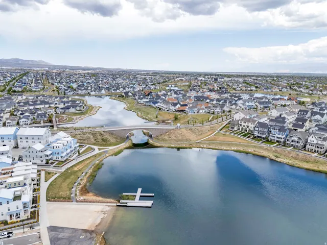 Expansive waterfront community featuring a large lake with a private dock, a pedestrian bridge, and numerous residential properties with diverse architectural styles