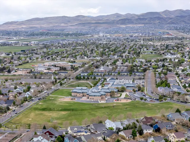Expansive suburban landscape featuring a variety of residential properties, mountainous terrain, and a large central green space