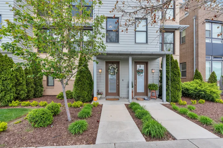 Modern townhome exterior featuring light gray siding with contrasting dark window frames