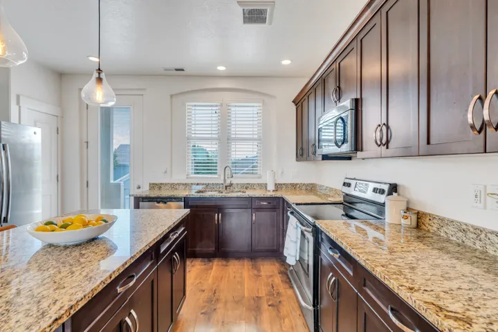 Kitchen featuring wood-finish flooring, dark wood cabinetry, and granite countertops