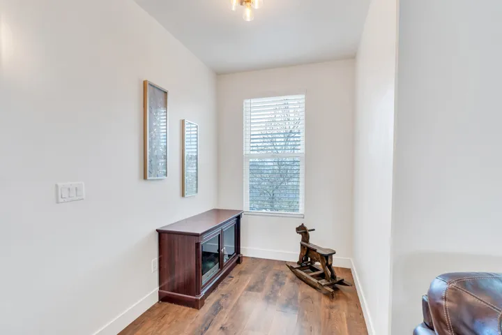 Room with wood-finish flooring, a single window with horizontal blinds, white baseboards, and a contemporary ceiling light fixture