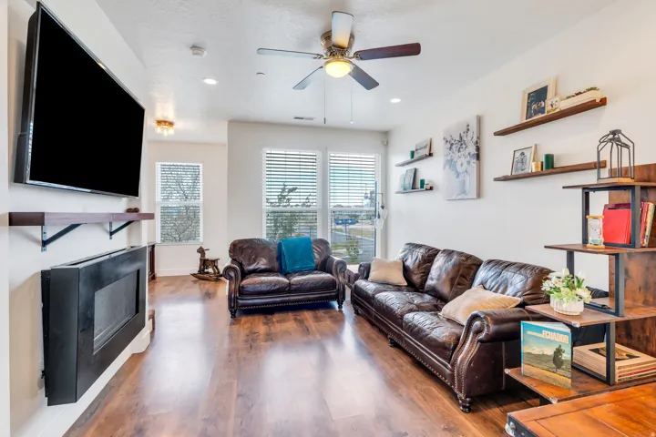 Spacious living area featuring wood-finish flooring, a ceiling fan, and recessed lighting