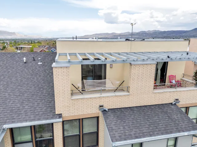 Upper-level balcony featuring cream brick construction, a metal pergola structure, and a glass sliding door