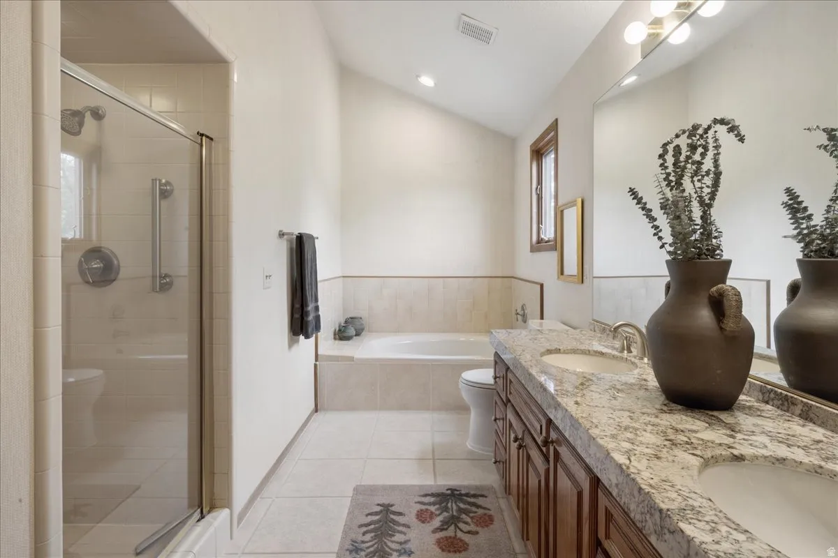 Primary bathroom featuring a dual vanity with a patterned countertop, wood cabinetry, and integrated sinks