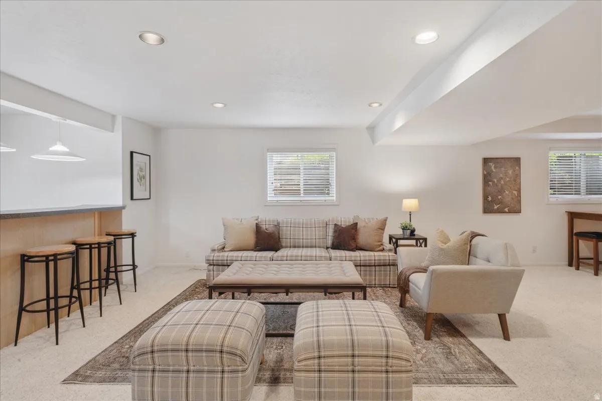 Recreation room featuring recessed lighting, light-colored carpeting, multiple windows with blinds, a built-in bar with a countertop, and pendant lighting