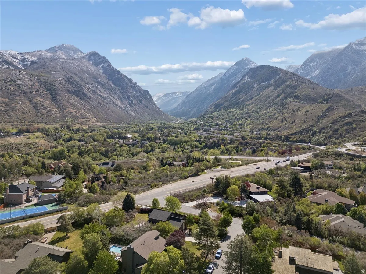 Expansive mountain valley scenery featuring a prominent range with snow-capped peaks. View looking into Little Cottonwood Canyon.