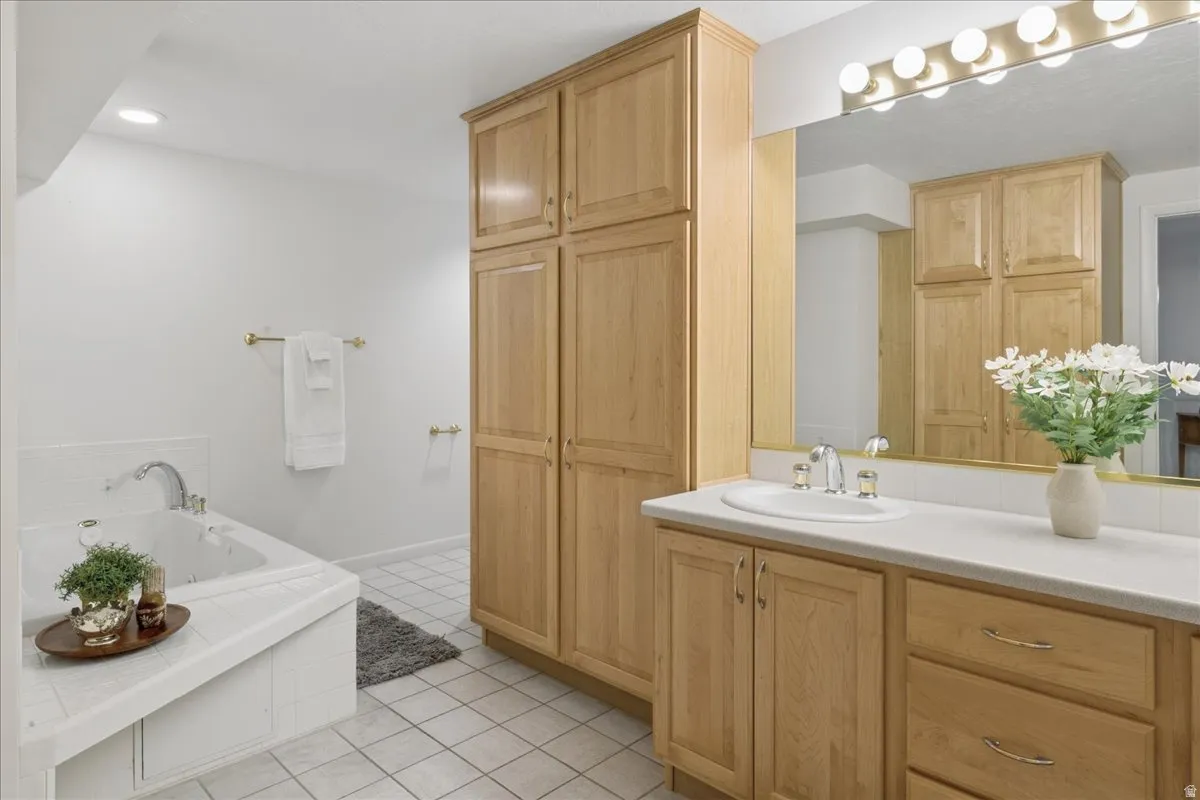 Full bathroom featuring a single vanity with light-tone cabinetry, a white countertop, and a built-in tub with white tile surround