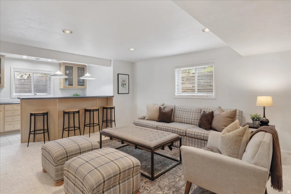 Lower-level living area featuring a built-in bar with light wood cabinetry, a dark countertop, and recessed lighting