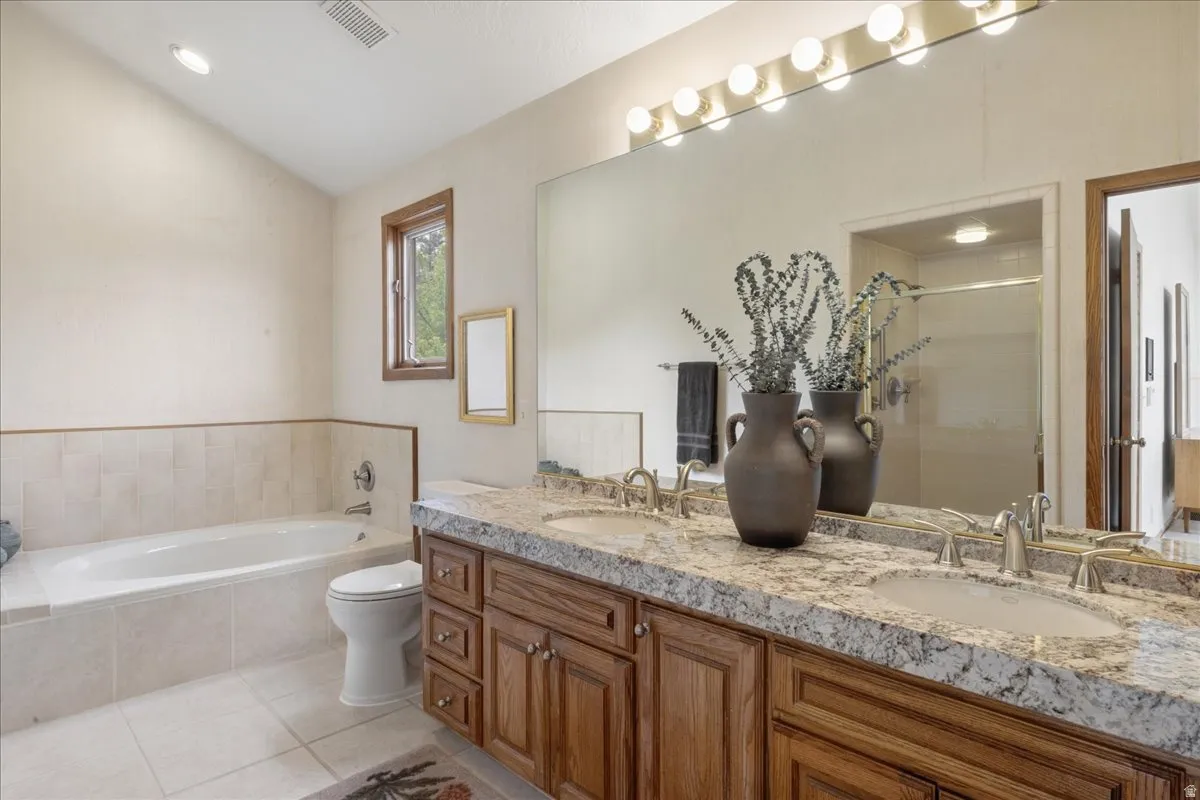 Primary bathroom with double vanity with undermount sinks and granite-style countertop, wood-finish cabinetry, and brushed nickel fixtures