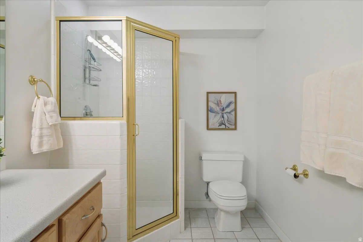Bathroom featuring a corner shower with a gold-finish frame, clear glass panels, and white subway tile surround