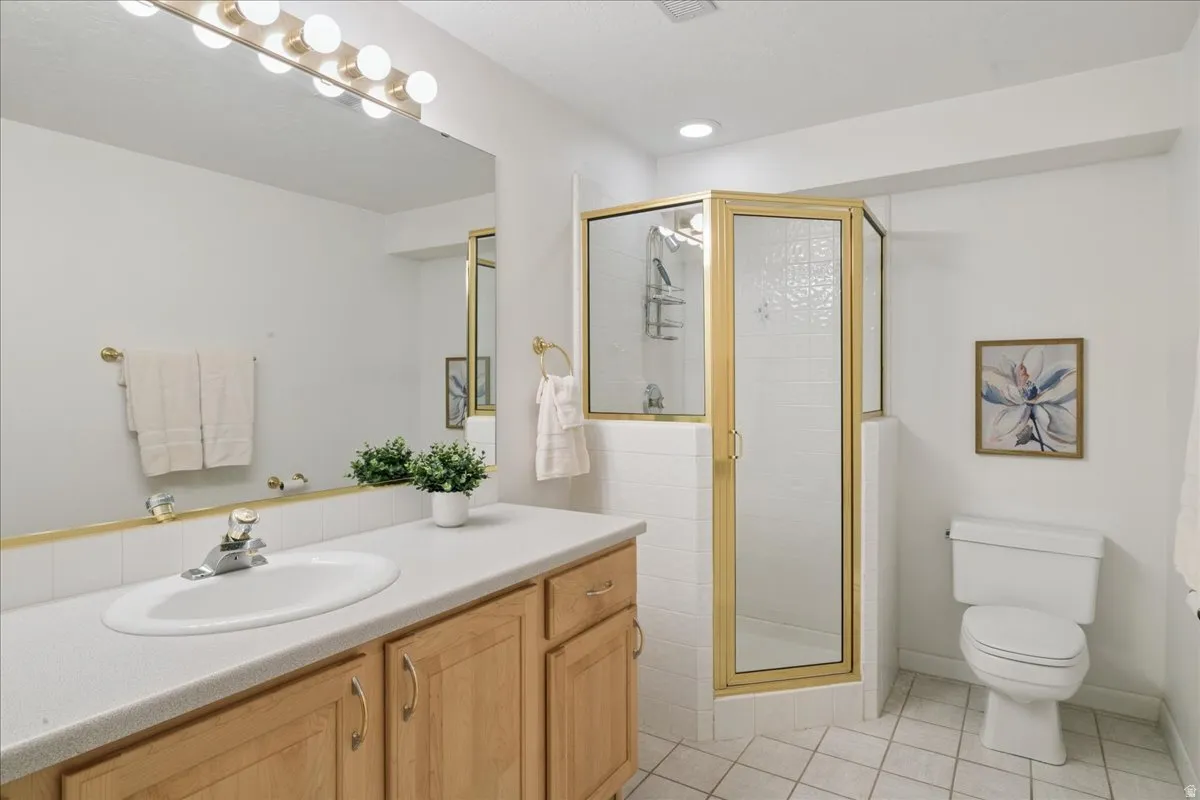 Bathroom with a light wood-finish vanity, integrated sink, and gold-tone fixtures