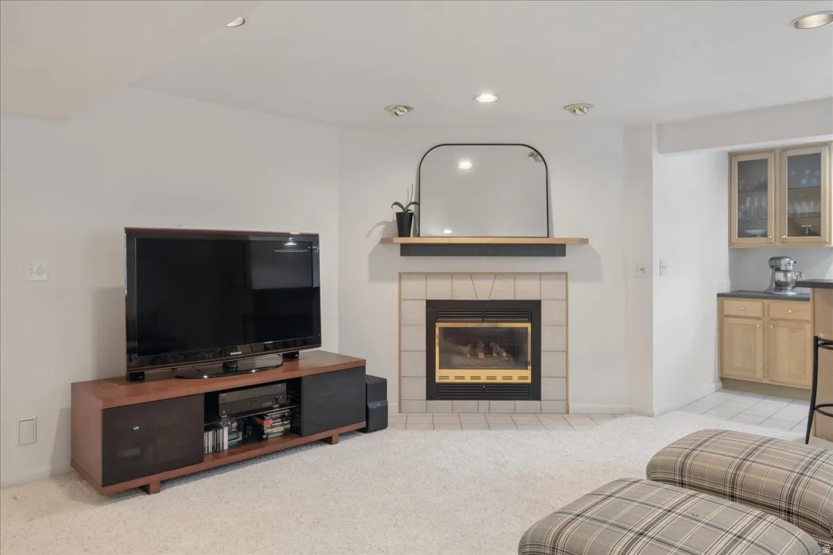 Cozy living area featuring a tiled fireplace with wood mantel, recessed lighting, and soft carpet flooring