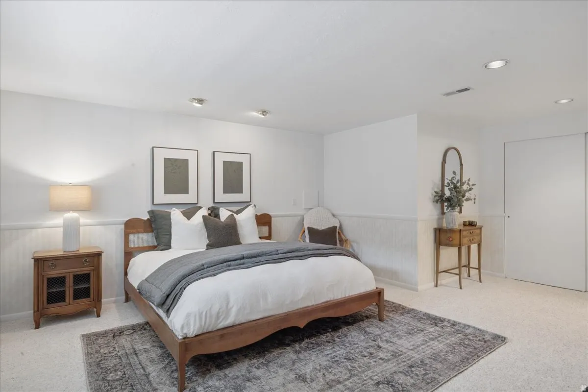Carpeted room featuring white walls, wainscoting, and recessed lighting
