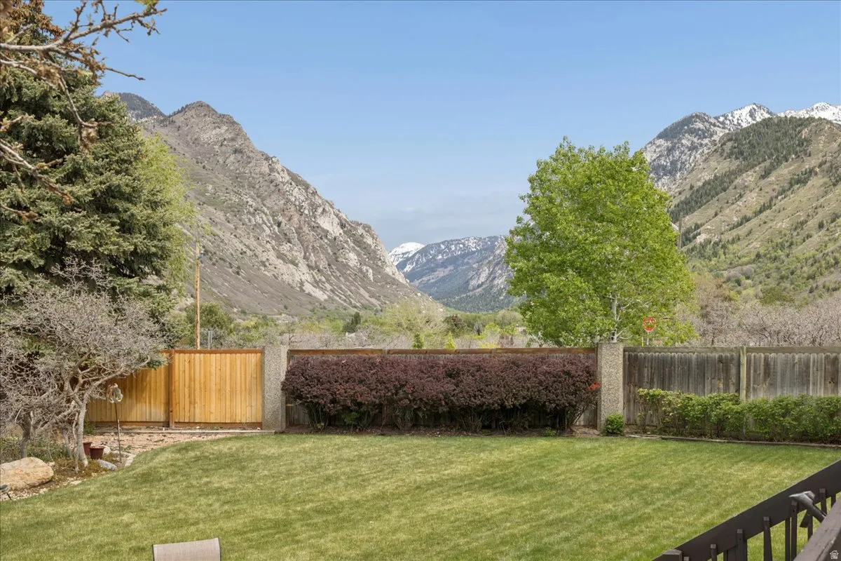 Expansive lawn with mountain backdrop, fenced perimeter, and mature landscaping