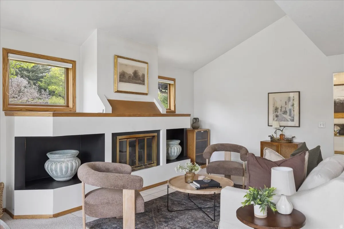 Living area featuring a prominent fireplace with a wood mantle and hearth, integrated shelving, and a vaulted ceiling