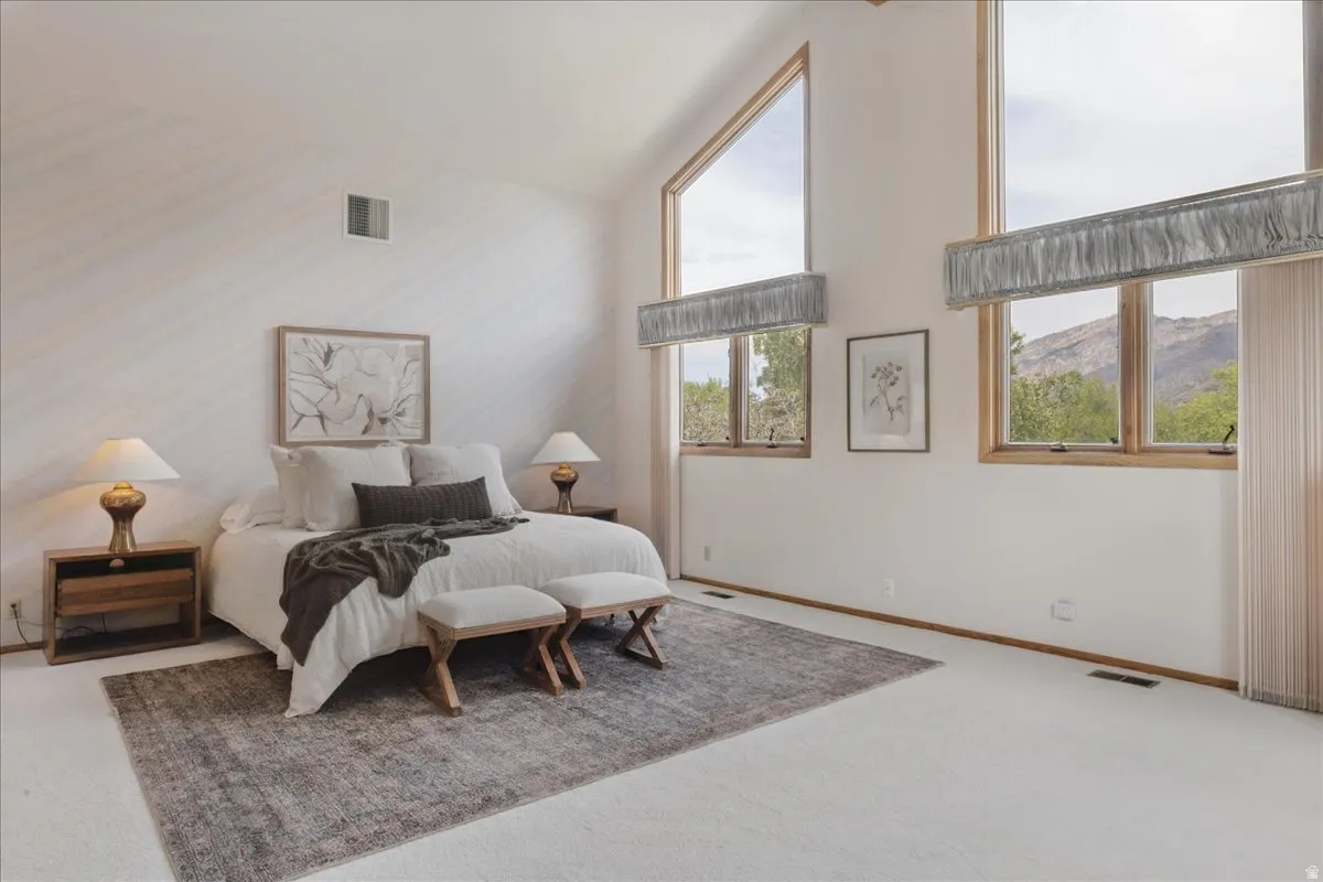 Spacious room featuring vaulted ceilings with exposed wood trim, multiple large windows, and wall-to-wall carpeting