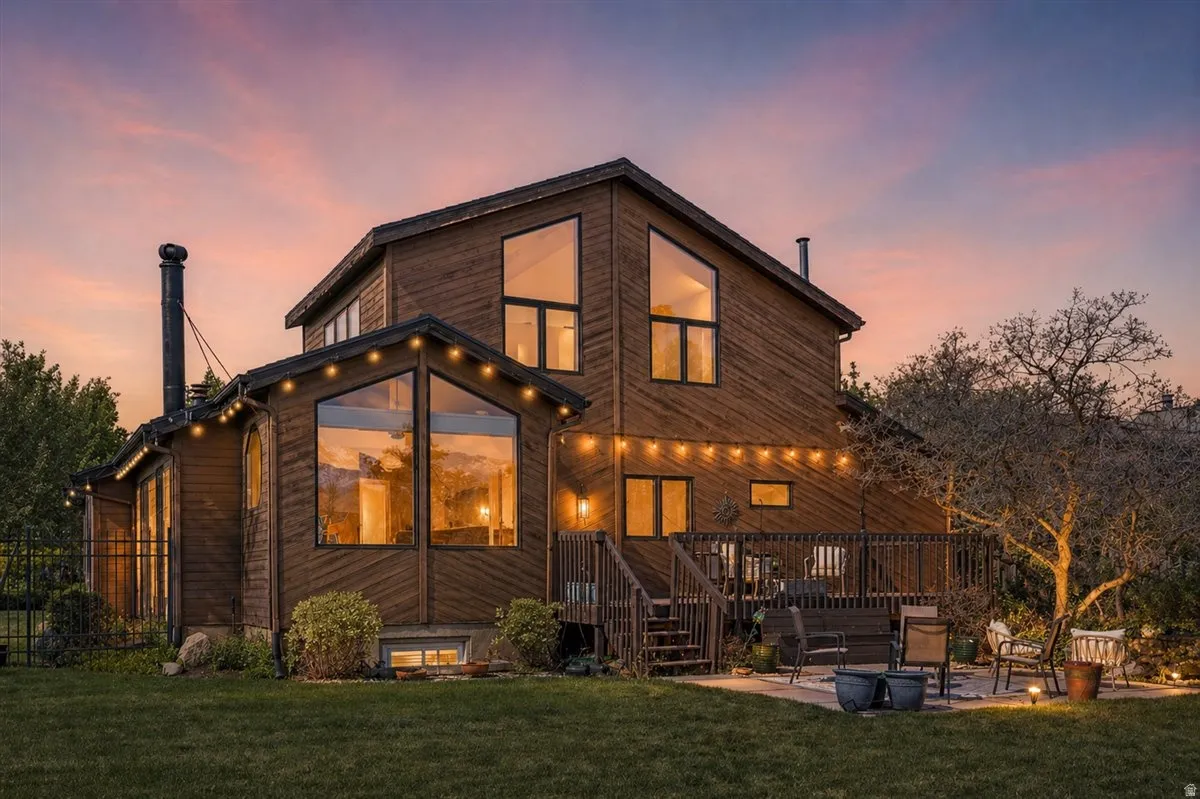 Wood-sided exterior featuring large picture windows, a multi-level wooden deck, and a manicured lawn