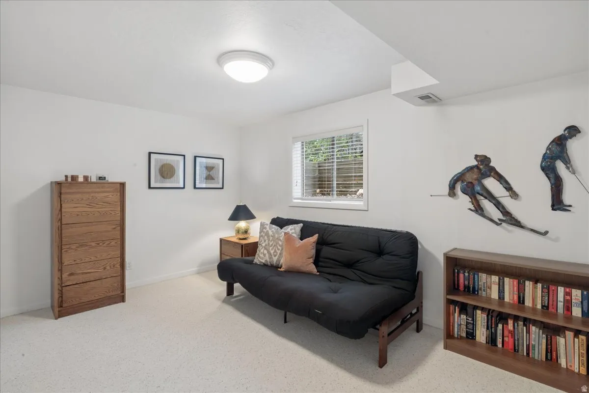 Carpeted room with a ceiling-mounted light fixture, white walls, and a window featuring horizontal blinds