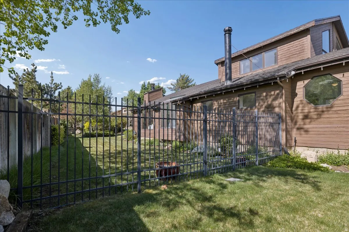 Expansive backyard featuring a manicured lawn, full-height privacy fencing, and a decorative metal fence