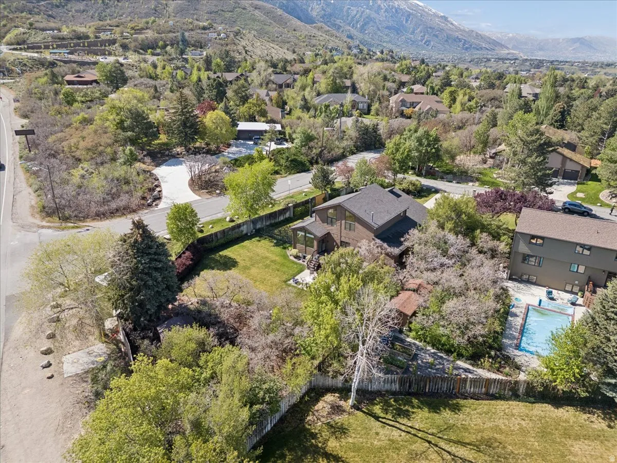 Aerial view showcasing a brown residence with a dark roof, surrounded by mature trees