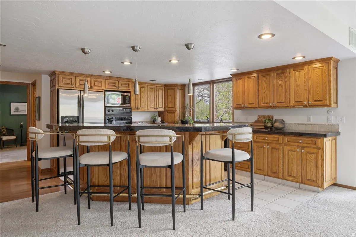 Kitchen featuring wood cabinetry, stainless steel appliances, a dark countertop, and a built-in breakfast bar