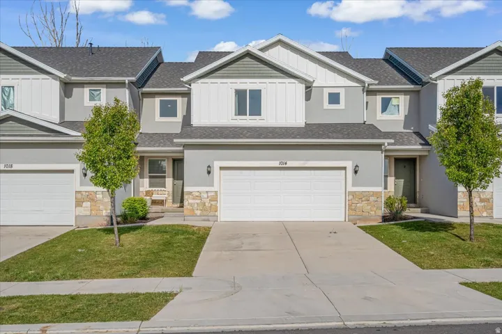 Craftsman-style house with board and batten siding, a front yard, stone siding, driveway, and a garage