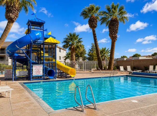 Resort-style pool area featuring a multi-story water slide structure with blue and yellow slides