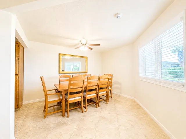 Dining area featuring tile flooring, a large window with blinds, and a ceiling fan