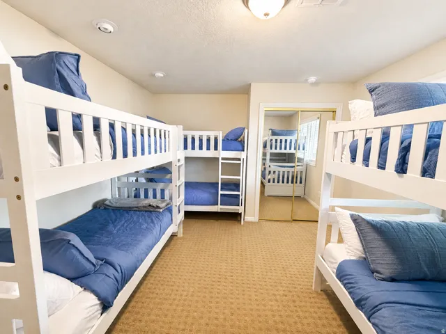 Bunk bed arrangements featuring white frames and a light-colored, textured carpet