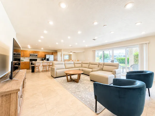 Open-concept living space featuring tile flooring throughout, recessed lighting, and a kitchen area with wood cabinetry and stainless steel appliances