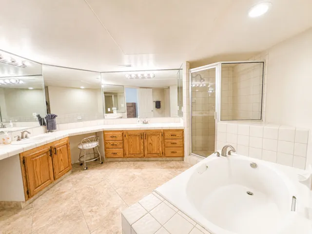 Spacious bathroom featuring an oval soaking tub, a separate glass-enclosed shower, and a curved vanity with dual sinks