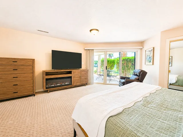 Sliding glass doors opening to a private patio, textured carpeting, and an entertainment console with a built-in electric fireplace