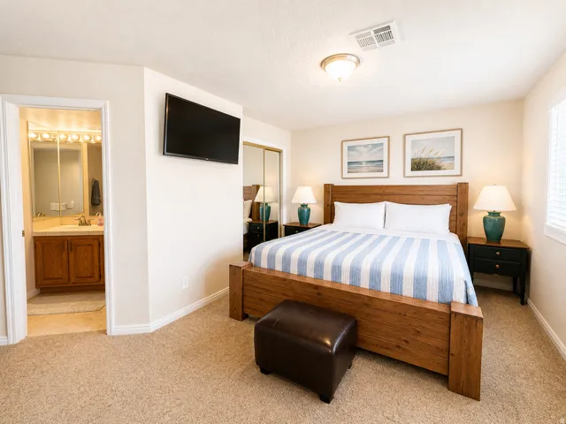 Carpeted bedroom featuring a ceiling light fixture, a wall-mounted television, and a sliding mirrored closet door