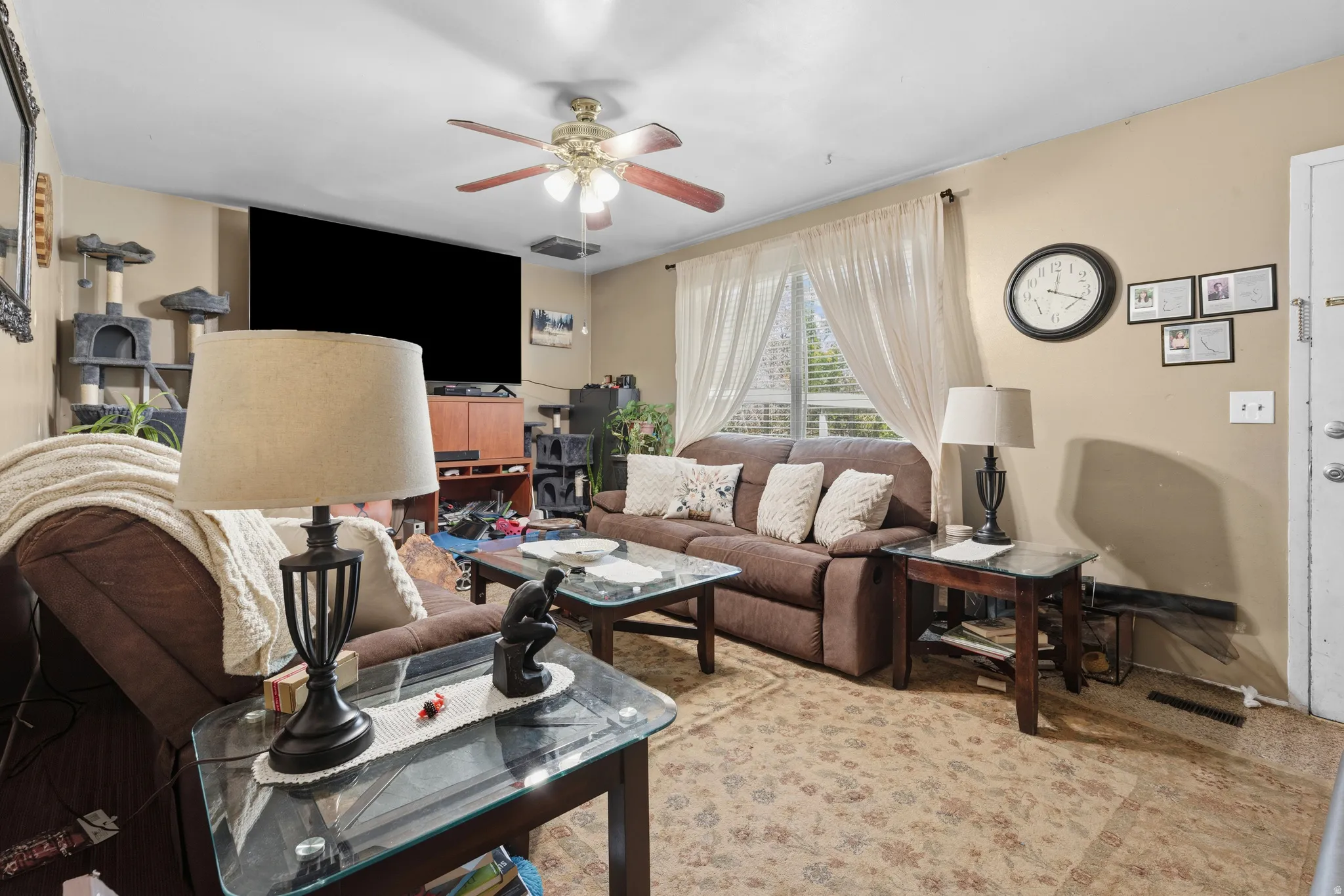 Living area featuring a ceiling fan, light neutral wall paint, and a window with sheer curtains