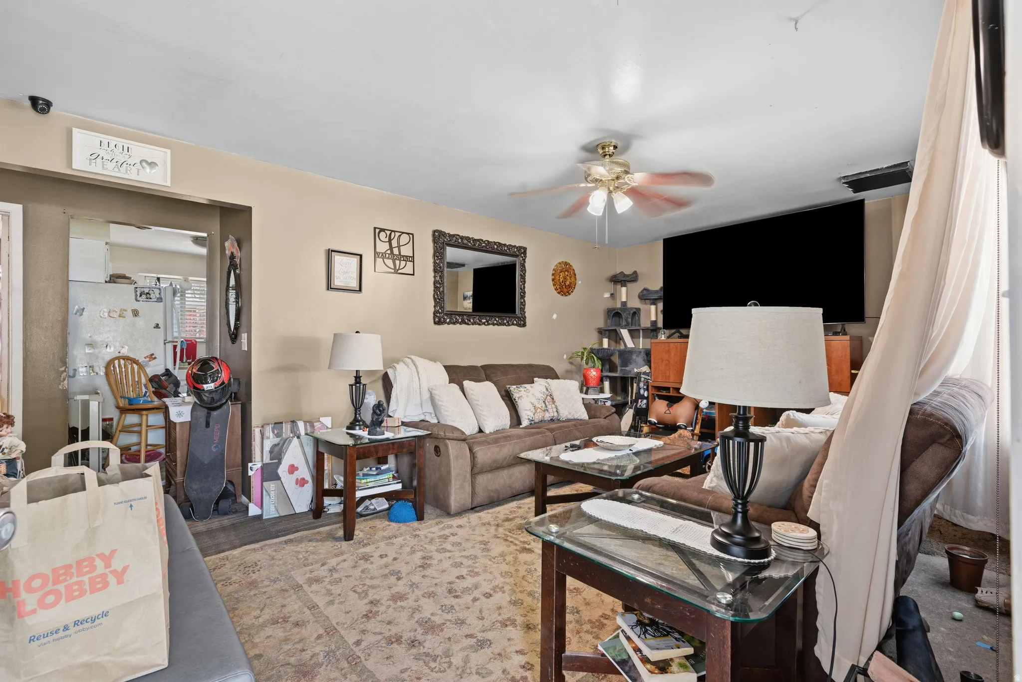 Spacious living area featuring light-toned walls, a ceiling fan, and a wide entryway