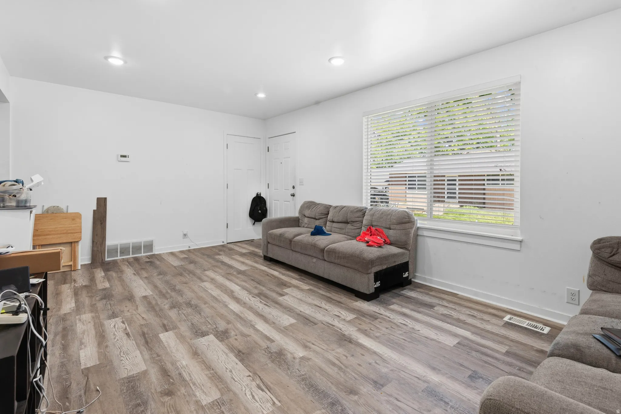 Spacious living area featuring wood-finish flooring, recessed lighting, and white walls