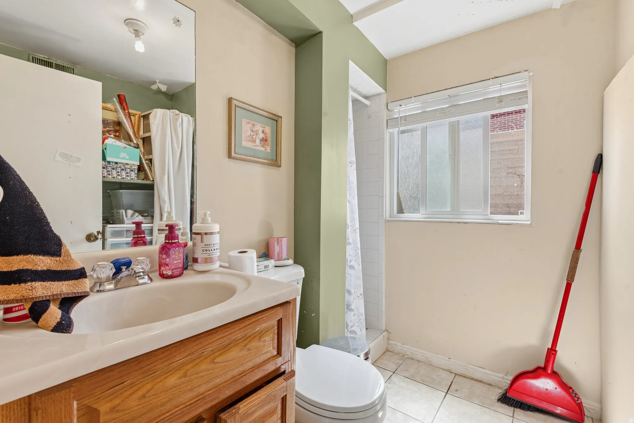 Bathroom featuring a vanity with a drop-in sink, wood-finish cabinetry, and a mirrored wall
